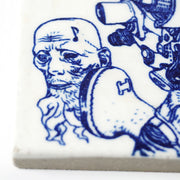 Close up of white ceramic tile with dark blue line art illustration, displaying a floating head of an old bearded man with a music note on his upper left temple.