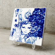 White ceramic square tile with a deep blue line art illustration of a girl with a mischievous expression looking off to the side. She wears a large helmet. A large bear has its mouth wide open in front of her face. Tile is on a clear acrylic stand.