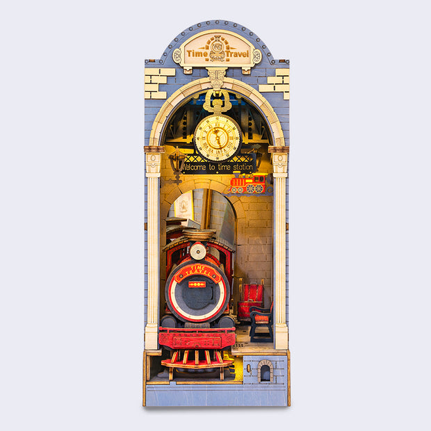 A vertical rectangular 3D bookend, with a whole miniature scene encapsulated in a book end. Scene is of a train going through a tunnel with a clock overhead.