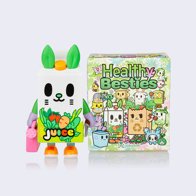 Vinyl figure of a cartoon style juice cartoon, with a smiling animal face. It holds a garden shovel in one hand and a pink watering can in the other. It stands next to its product packaging.