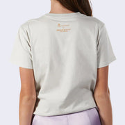 Back view of a light gray, beige-ish fitted shirt, with a tokidoki x Hello Kitty and Friends logo along the top center.