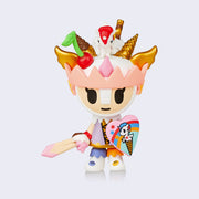Amerena figure, a human warrior with a white and pink helm, decorated like an ice cream sundae with a cherry, cones and cookie sticks on top with a small baby unicorn. She holds a heart shaped shield and a sword with a scoop of Neapolitan ice cream as the hilt.