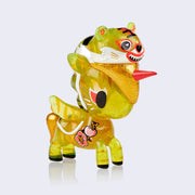 Vinyl clear neon yellow unicorn figure with glitter injection and golden stripes all over its body like a tiger. It has a small appliqué illustration of two tigers in pink flowers on its side and wears a tiger head hat.