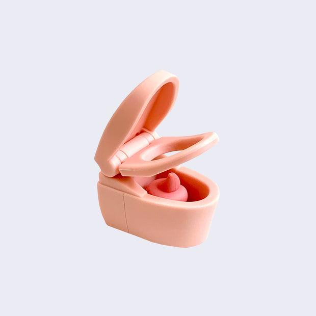 A light peach pink plastic eraser shaped like a toilet with its lid raised to reveal a swirled pink poo inside.