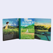 Open spread of inside of postcard set for art from My Neighbor Totoro, featuring a small text blurb and full bleed graphics of a lush countryside.