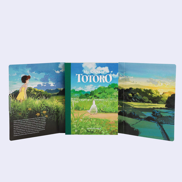 Open spread of inside of postcard set for art from My Neighbor Totoro, featuring a small text blurb and full bleed graphics of a lush countryside.