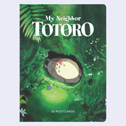 Cover of a set of postcards from My Neighbor Totoro, featuring an illustration of Totoro laying in a lush green forest with a small girl on his chest.