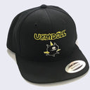 Front side of black hat. Stitched on front is a one-eyed monster with wings. Above the monster is yellow stylized text that says ugly doll.