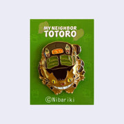Enamel pin of a smiling Catbus, crouched down as if about to bound up. On a green backing card with "My Neighbor Totoro" written across the top.