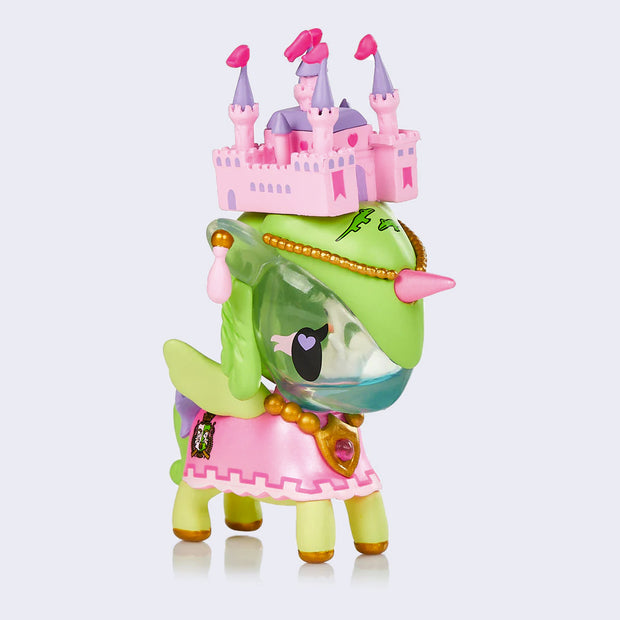 Vinyl "Swan Princess" unicorno figure. A green unicorn with pink accents, dressed like a princess with a pink and purple play castle on its head. It's face is hollow and inside is a swan in water.